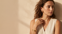 Woman wearing layered gold necklaces, huggie earrings and gold rings