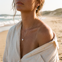 Woman at the beach wearing a pearl pendant necklace and pearl drop earrings – Marliva