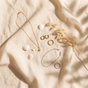 Gold and silver-tone jewellery laid out on linen with seashells – Marliva