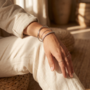 Silver-tone bracelet stack and rings on a woman's wrist against a linen sleeve – Marliva