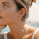 Model wearing Remi gold T-bar hoop earrings