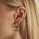 Remi gold T-bar hoops worn in an ear stack